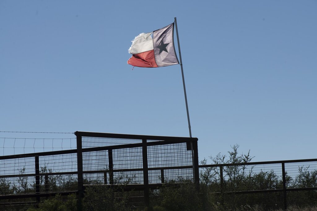 Texas flag waving over rural Texas farmland at harvest time